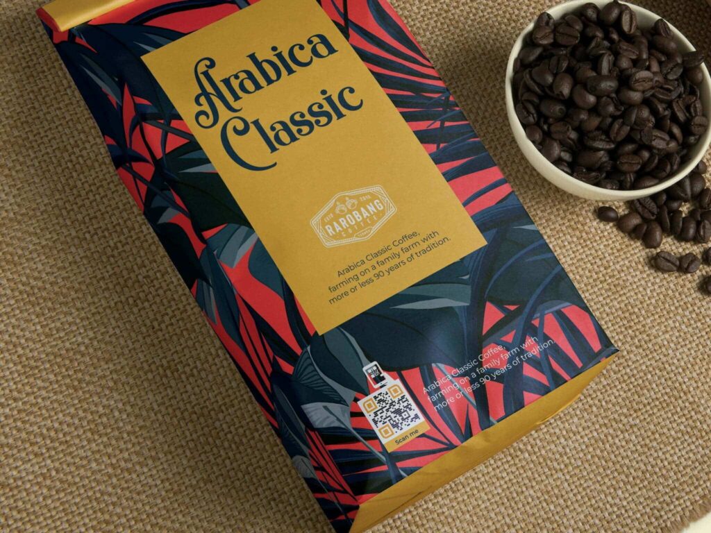 an arabica classic bag of coffee with red, navy, and gold packaging and a gs1 digital link qr code, next to a cup of coffee beans