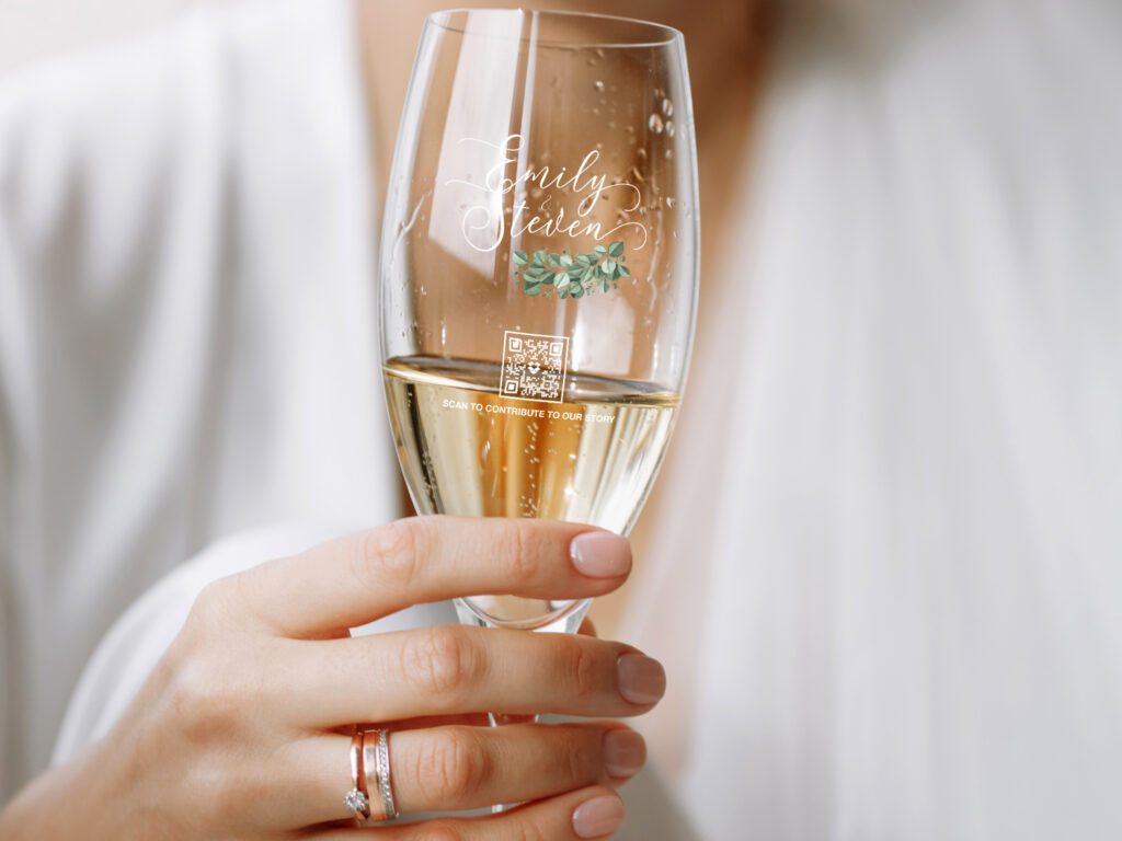 qr code on a champagne flute held by a woman's hand with weddings rings on her finger
