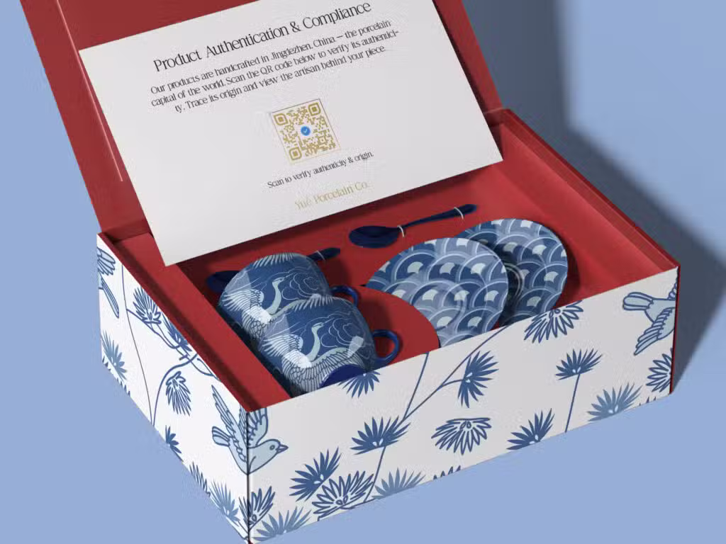 Some blue and white porcelain cups with cranes on them in a red-lined box with a QR code on the packaging inside.