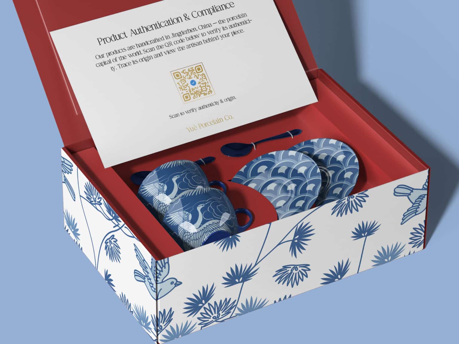 Some blue and white porcelain cups with cranes on them in a red-lined box with a QR code on the packaging inside.