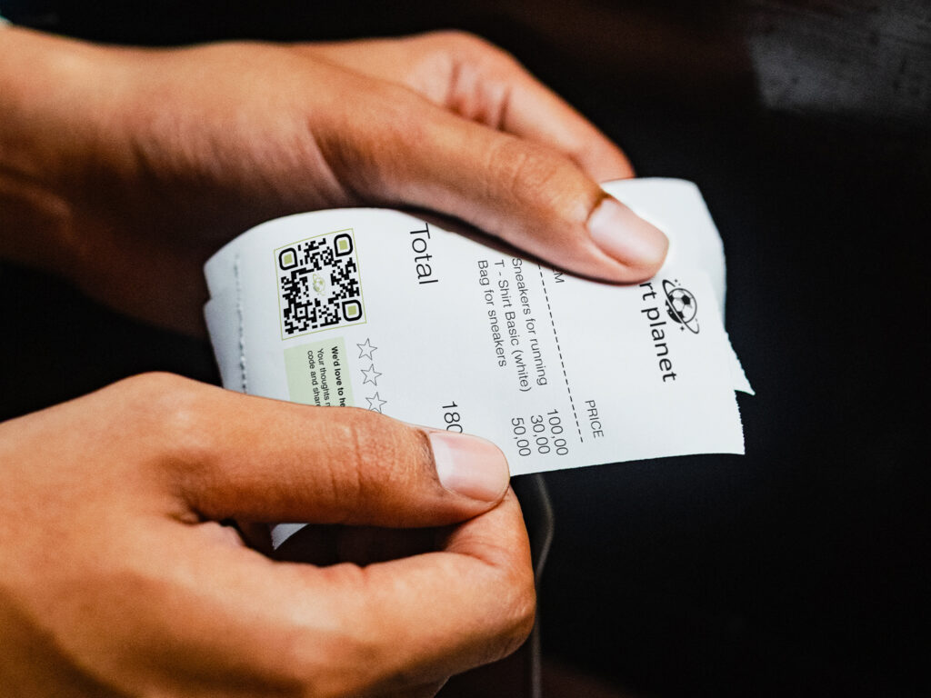 a lady's hands holding a receipt with a qr code for reviews